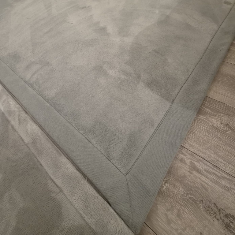 Loartee Spielteppich Krabbelwiese Baden-Baden Grauer Teppich auf einem hölzernen Boden, mit sichtbaren Nahtdetails an den Kanten.