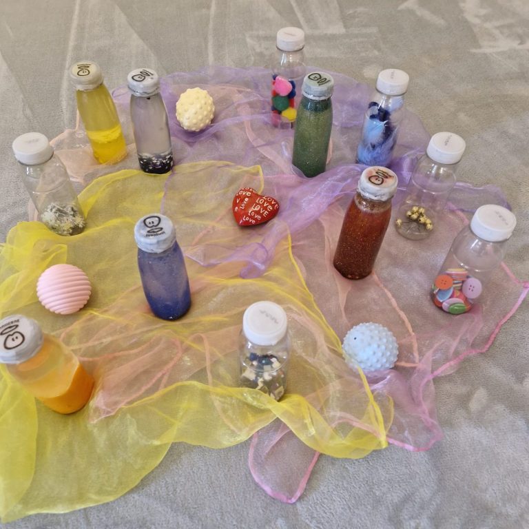 Bunte Flaschen mit verschiedenen Inhalten liegen auf bunten Tüchern.