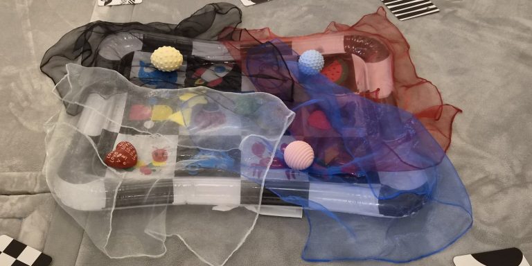 Bunte Netze umhüllen verschiedene Spielzeugartikel auf einem Tisch.