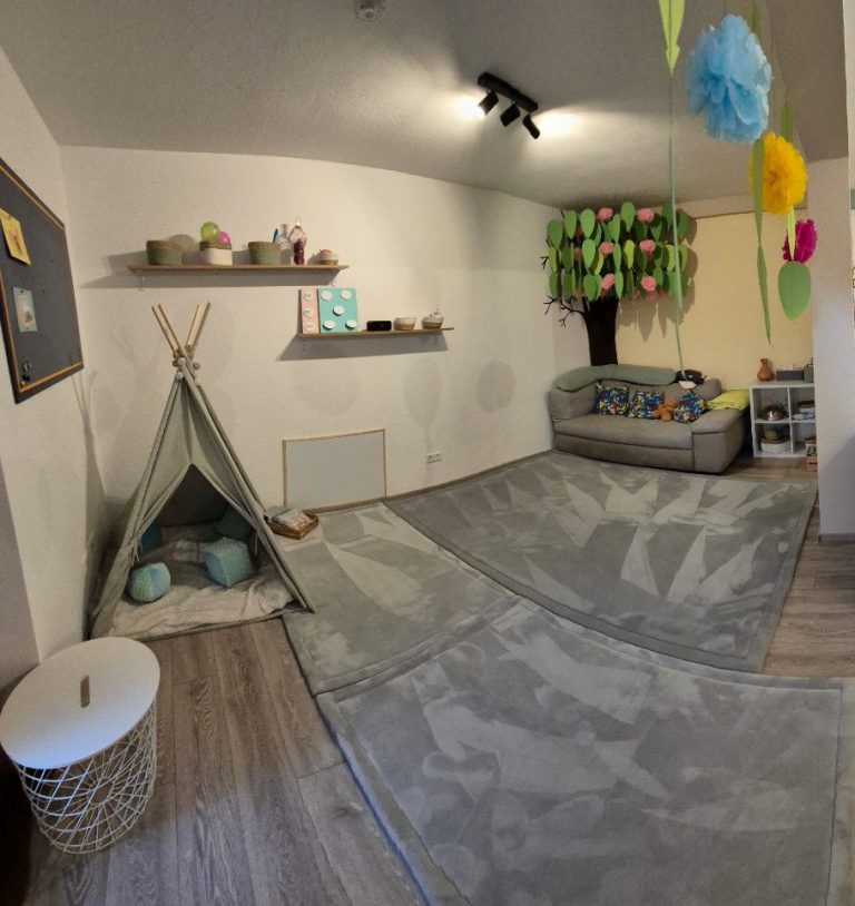 Spielzimmer mit Tipi, Sofa, bunten Dekorationen und einem Teppich.