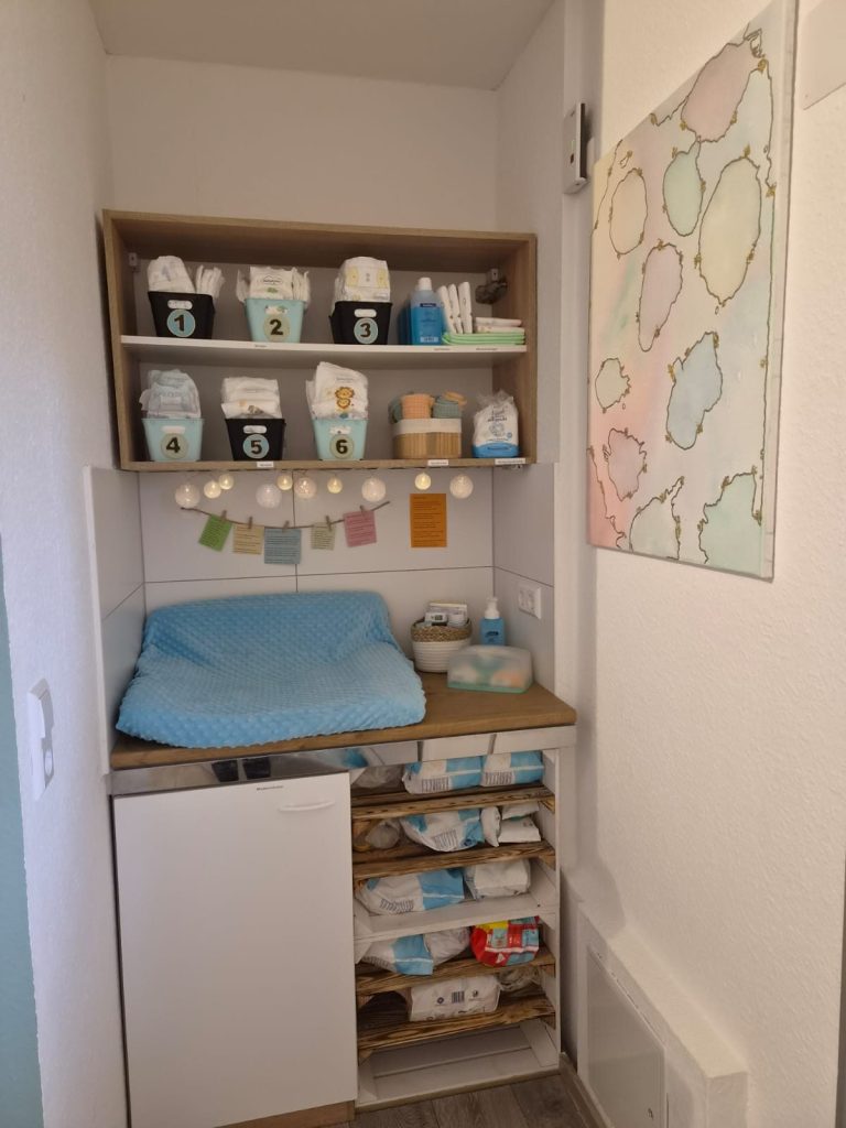 Kleinraum mit Regalen, gefüllt mit Babyartikeln und bunten Dekorationen.